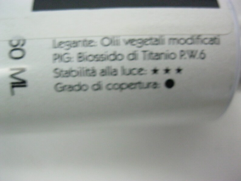 May include: A close-up of a white tube with black text. The text reads: "Legante: Oli vegetali modificati PIG: Biossido di Titanio P.W.6 Stabilit&agrave; alla luce: *** Grado di copertura: 50 ML"