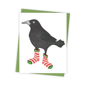 May include: A black bird with red and green striped socks. The bird is standing on a white background.