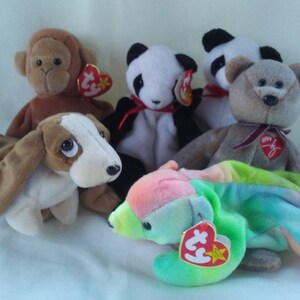 May include: Five plush beanie baby toys, including a brown monkey, a white and black panda, a brown and white basset hound, a gray bear, and a multi-colored tie-dye toy.