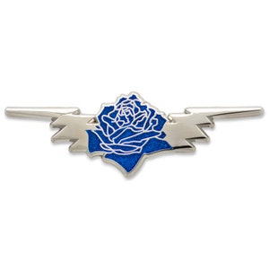 May include: A silver-toned metal pin featuring a blue rose design with glitter accents. The rose is set within a stylized lightning bolt shape. The pin is designed to be worn as a decorative accessory.