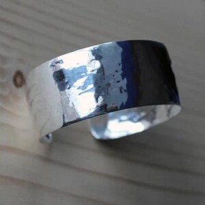 May include: A silver hammered cuff bracelet with a smooth, polished finish.