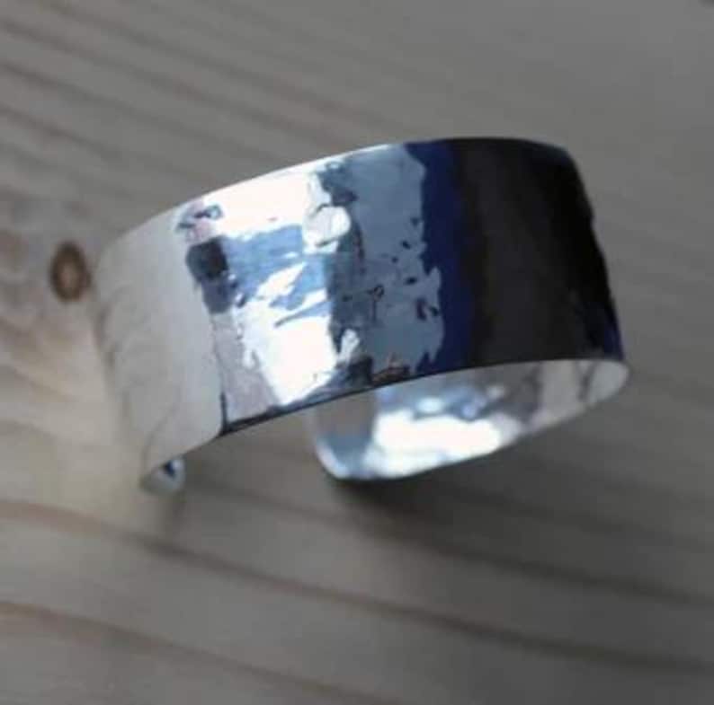 May include: A silver hammered cuff bracelet with a smooth, polished finish.