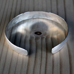 May include: A silver bangle bracelet with a brushed finish.