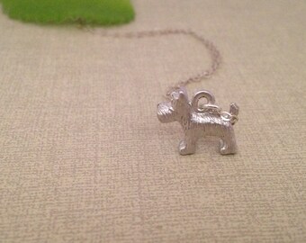 May include: A silver necklace with a small, detailed, silver dog charm.