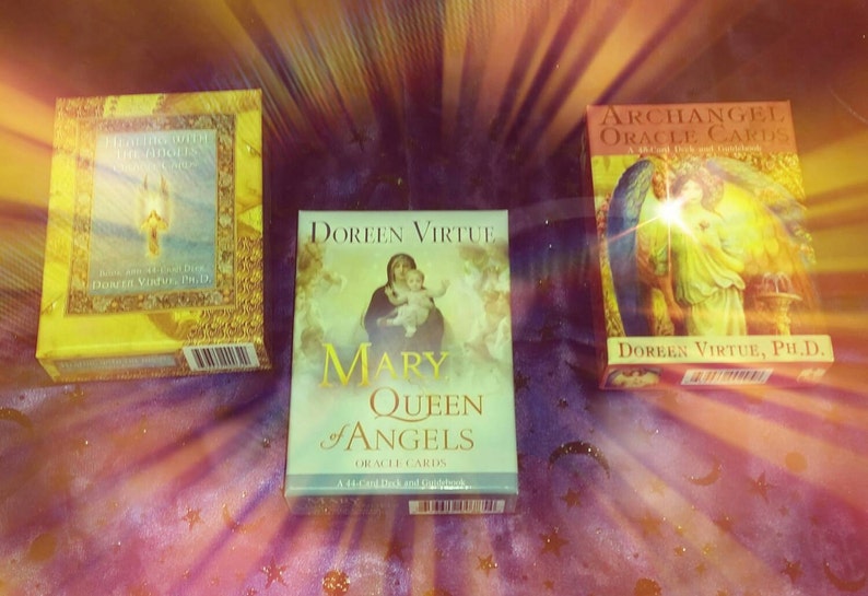 May include: Three oracle card decks by Doreen Virtue. The decks are titled "Archangel Oracle Cards", "Mary Queen of Angels Oracle Cards", and "Healing with the Angels Oracle Cards".