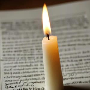 Puede incluir: Una vela blanca con una llama amarilla que arde sobre una página de un libro con tinta negra.