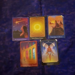 Puede incluir: Cinco cartas de tarot dispuestas sobre una superficie azul oscuro. Las cartas presentan ilustraciones y texto, incluyendo "Accelerated Motion", "Solar Plexus Chakra", "Suffering in Silence", "Movement, Choices, Decisions" y "BALANCE".