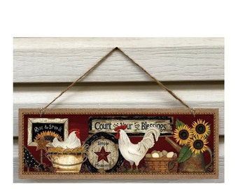 Può includere: Un cartello in legno rustico con sfondo rosso e bordo in juta. Il cartello presenta un gallo, due galline, girasoli e un annaffiatoio. Il testo sul cartello recita "Count Your Blessings", "Simple Pleasures" e "Rise & Shine".