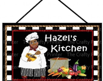 Może przedstawiać: Czarno-biały znak w kratkę z obramowaniem z sznurka. Na znaku widnieje napis "Hazel's Kitchen" białymi literami. Rysunkowy kucharz w białym czepku i czerwonej bandanie trzyma miskę i trzepaczkę. Kucharz stoi przed garnkiem z zupą i warzywami.