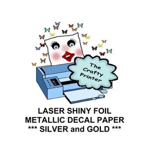 May include: A blue printer with a white pillow face and butterflies around it. The text "The Crafty Printer" is in a speech bubble. The text "LASER SHINY FOIL METALLIC DECAL PAPER *** SILVER and GOLD ***" is below the printer.