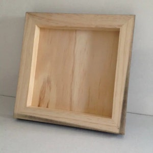 May include: A plain wooden frame with a natural wood finish. The frame is square and has a simple design.