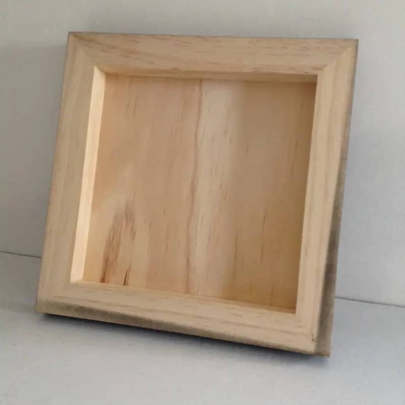 May include: A plain wooden frame with a natural wood finish. The frame is square and has a simple design.