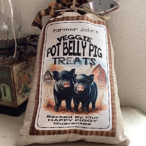 May include: A burlap bag with a brown and white plaid border and a label that reads "Farmer John's Veggie Pot Belly Pig Treats" with an image of two black piglets. The label also says "Backed By Our Happy Piggy Guarantee".