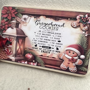 May include: A wooden sign with a gingerbread man and a lantern, with a recipe for gingerbread cookies. The recipe includes ingredients like brown sugar, molasses, butter, flour, baking soda, cinnamon, ginger, allspice, and clove. The sign also says "Bake at 375° for 10 min - Enjoy".