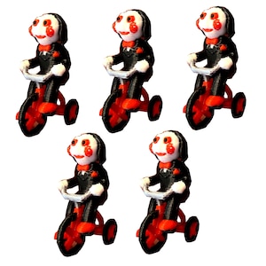 May include: Five identical figurines of a white-faced character with red spiral cheeks, wearing a black suit with a red bowtie, riding a red tricycle with black wheels. The figures have black hair and are positioned in a group against a white background.