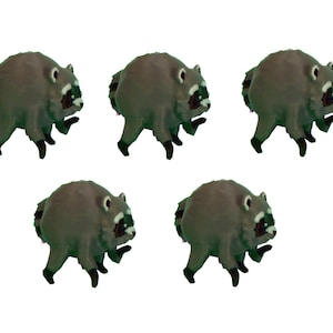May include: Five small, round, gray and black raccoon figurines arranged in a grid. Each figurine features a plump body, short legs with dark paws, a striped tail, and a distinct black mask pattern around the eyes on a white face.