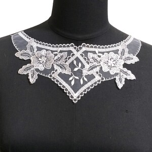 May include: White lace trim featuring a floral design. The lace is delicate and intricate, with a scalloped edge. It is ideal for adding a touch of elegance to any project.