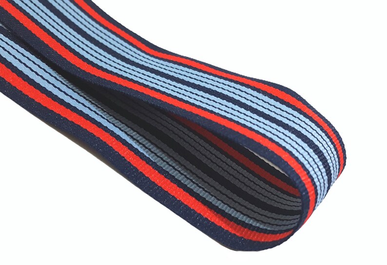 May include: A close-up of a blue and red striped ribbon. The ribbon is made of a woven fabric and has a subtle sheen.