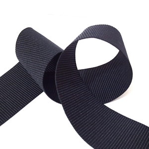 May include: Black grosgrain ribbon with a ribbed texture. The ribbon is folded in a loop shape.