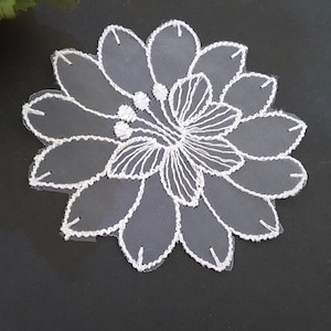 May include: White lace flower applique with a delicate floral design. The applique is made of sheer fabric and has a scalloped edge.