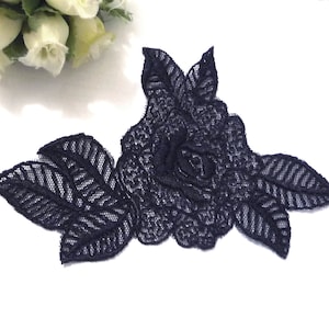 May include: A navy blue lace applique featuring a large rose with leaves. The rose is detailed with intricate stitching and the leaves have a striped pattern.