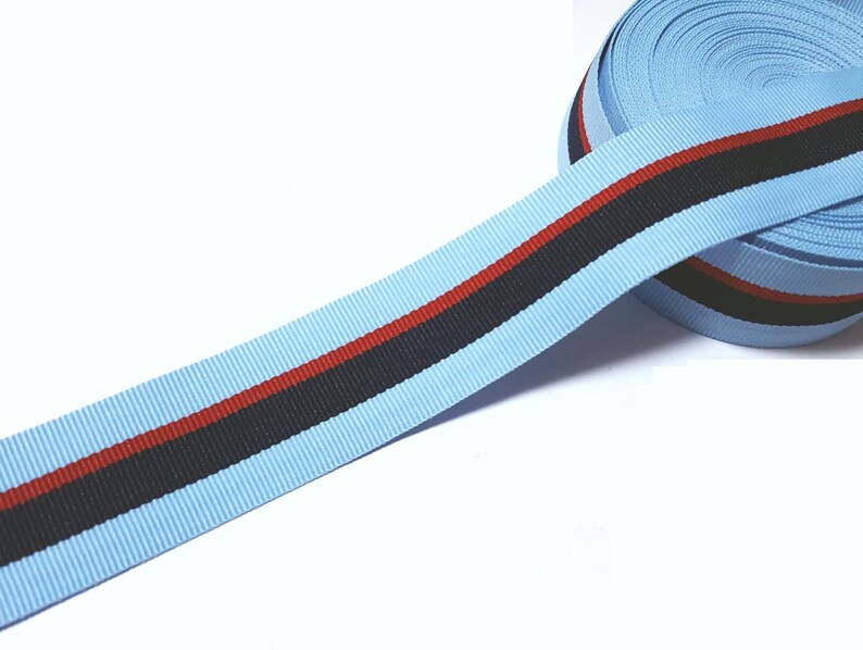 May include: A light blue ribbon with a black and red stripe. The ribbon is rolled up and ready to be used for crafts or decorations.