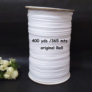 May include: A white elastic band on a cardboard roll. The roll is labeled "400 yds / 365 mts original Roll".