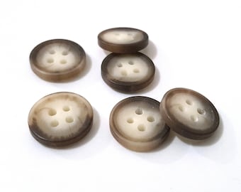 May include: Six brown and white four-hole buttons. The buttons have a light brown outer ring and a white center with four holes.