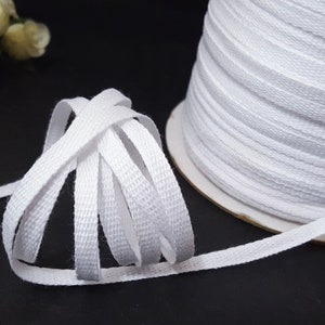 May include: A spool of white cotton twill tape. The tape is woven with a subtle texture and is approximately 1/2 inch wide.