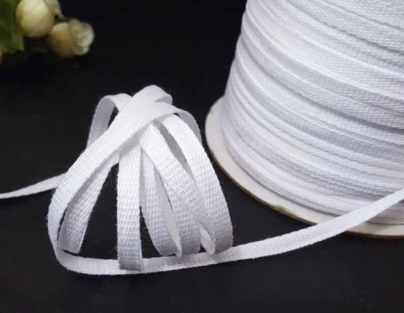 May include: A spool of white cotton twill tape. The tape is woven with a subtle texture and is approximately 1/2 inch wide.
