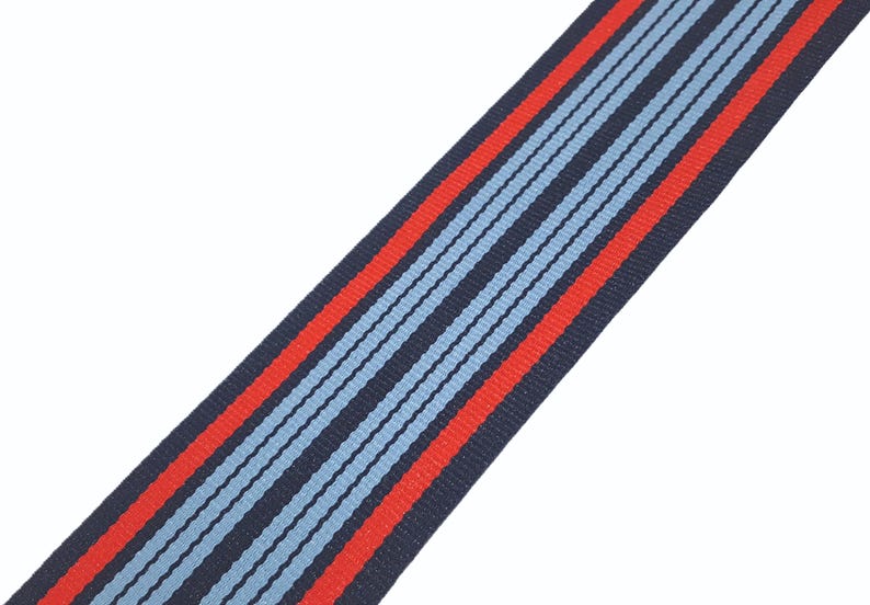 May include: A blue and red striped ribbon with a white background. The ribbon is made of a woven fabric and has a subtle texture.