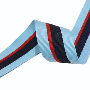 May include: Light blue ribbon with a black and red stripe. The ribbon is woven and has a subtle texture.