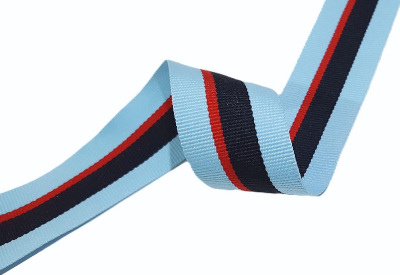 May include: Light blue ribbon with a black and red stripe. The ribbon is woven and has a subtle texture.