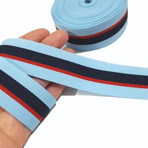 May include: Light blue ribbon with a red and navy blue stripe. The ribbon is approximately 1 inch wide.