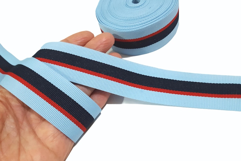 May include: Light blue ribbon with a red and navy blue stripe. The ribbon is approximately 1 inch wide.