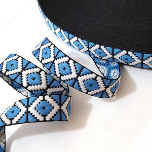 May include: Blue and white patterned trim with black accents. The trim is woven and has a geometric design.