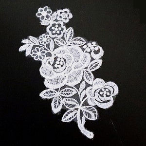 May include: White lace applique featuring a floral design with a large rose and smaller flowers. The applique is ideal for adding a touch of elegance to clothing, crafts, or home decor.