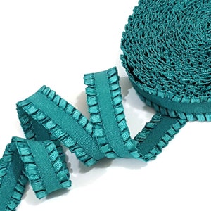 May include: Teal blue ruffled trim with a satin finish. The trim is rolled up and shows the ruffles in detail.