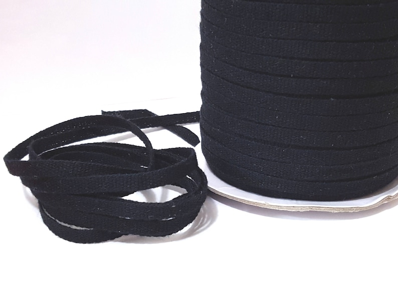 May include: A spool of black cotton cord, wound tightly and ready to be used for crafting projects.