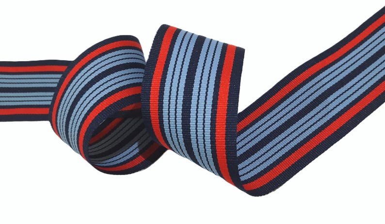May include: Red and blue striped ribbon with a woven texture. The ribbon is folded and twisted, showing the pattern.