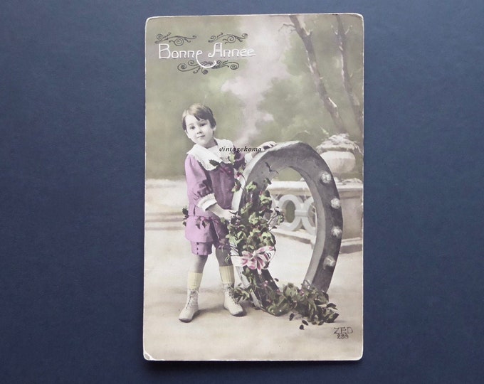 Antique Happy New Year Postcard. Little boy bringing good luck. Horseshoe. Holly branches. Holiday season. French postcard