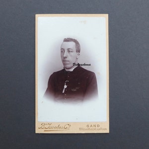 Fotografia di un giovane sacerdote, 1900. CDV. B. Jacobs & Co. Gand. Belgio. Tonaca. Colletto romano. Medaglione della Vergine Maria