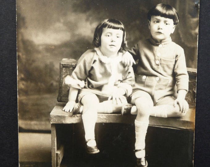 Photo 2 enfants assis sur un banc. Carte postale originale noir et blanc. Coiffure enfantine. Soulier. Vêtement. Mode enfantine 1900.