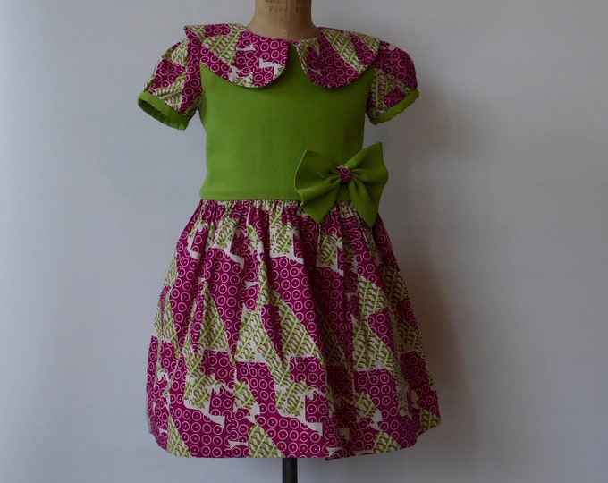 Green and fuchsia pink girl's dress in African print fabric. Classic short balloon sleeves and Peter Pan collar. 1980.