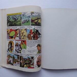 May include: A comic book open to a page with colourful illustrations of people and a landscape. The page is filled with speech bubbles and text. The right page is blank.