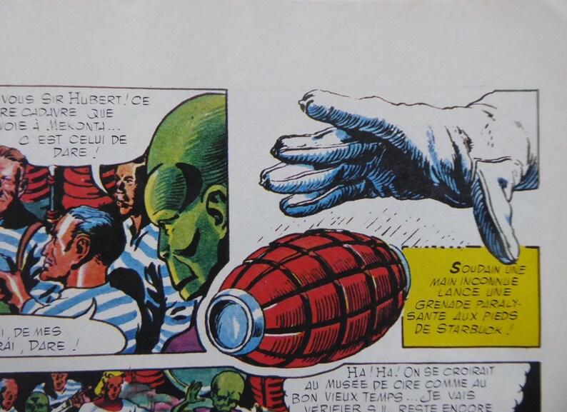 May include: A comic book panel featuring a green alien with a red and black grenade. The text in the panel reads "VOUS SIR HUBERT!CE RE CADAVRE QUE WOIE MEKONTA CEST CELUI DE DARE!" and "SOUDAIN UNE MAIN INCONNUE LANCE UNE GRENADE PARALY-SANTE AUX PIEDS DE STARBUCK!"