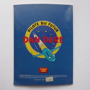May include: A blue and yellow comic book cover with the title "PILOTE DU FUTUR DAN DARE" in red and white letters. The cover features a blue and white spaceship flying through a yellow and white trail.