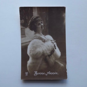Carte postale Bonne année 1914. Jeune femme avec cape de fourrure blanche.  Temps des fêtes. Carte postale française
