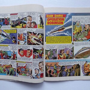 May include: A comic book page featuring Dan Dare, Operation Robinson. The page is filled with colourful illustrations of spaceships, characters, and a futuristic setting. The text reads "Dan Dare, Operation Robinson".