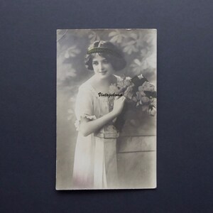 Carte postale jeune femme 1900-10. Monochrome. Gerbe de fleurs. Robe encolure dentelle. Cie international des beaux arts, Montréal.